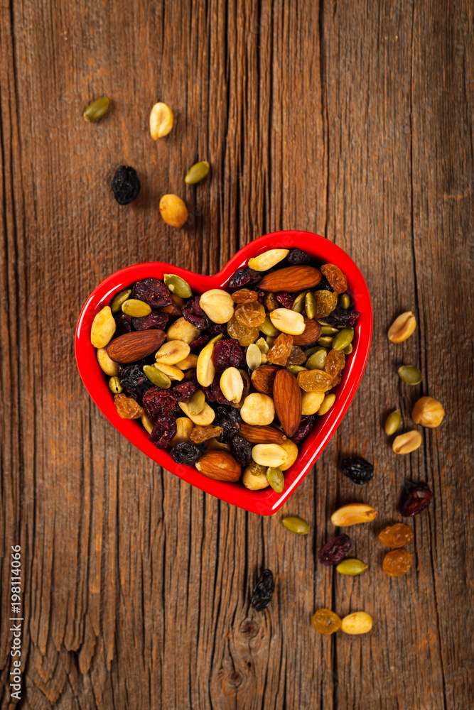 Energy Blend Trail Mix with Nuts and Dried Fruits in Heart Shaped Bowl. Selective focus. Energy Blend Trail Mix with Nuts and Dried Fruits in Heart Shaped Bowl. Selective focus.