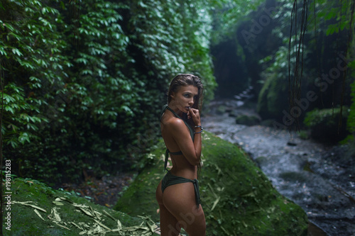 Beautiful girl with a sexy body among tropical jungle

