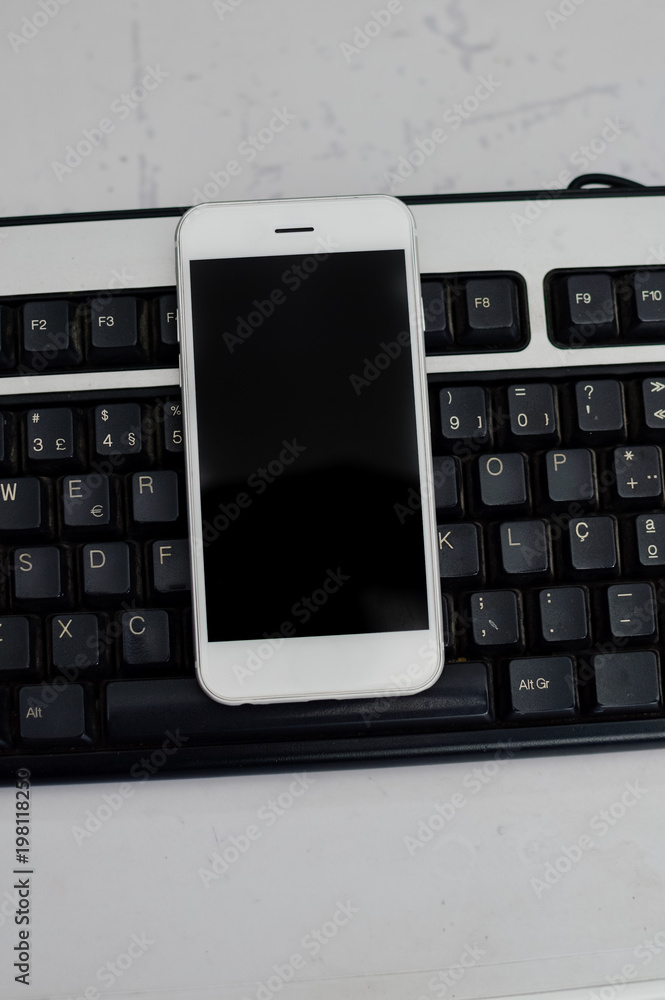 Mobile phone and computer keyboard on light table, communication technology background. Digital concept or gadgets support service, close up top view of electronic devices Mobile phone and computer keyboard on light table, communication technology background. Digital concept or gadgets support service, close up top view of electronic devices