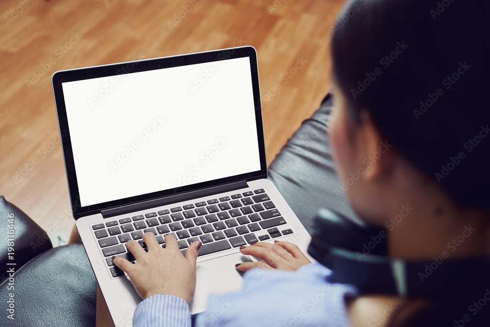 A woman uses an empty laptop screen in a room on a black sofa. And wear black headphones. Listen to music. A woman uses an empty laptop screen in a room on a black sofa. And wear black headphones. Listen to music.