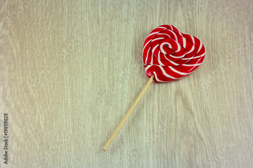 Lollipop in shape of heart on wooden background