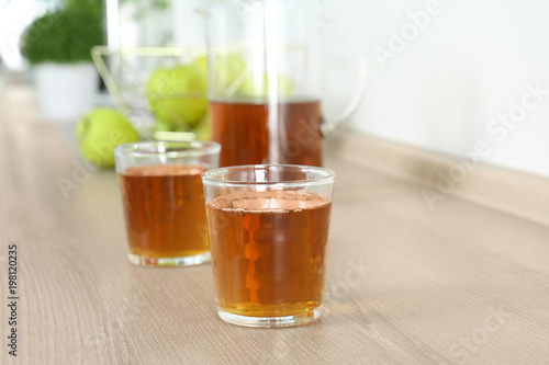 Glasses of fresh apple juice on wooden table