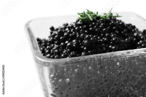 Glass bowl with black caviar on white background, closeup