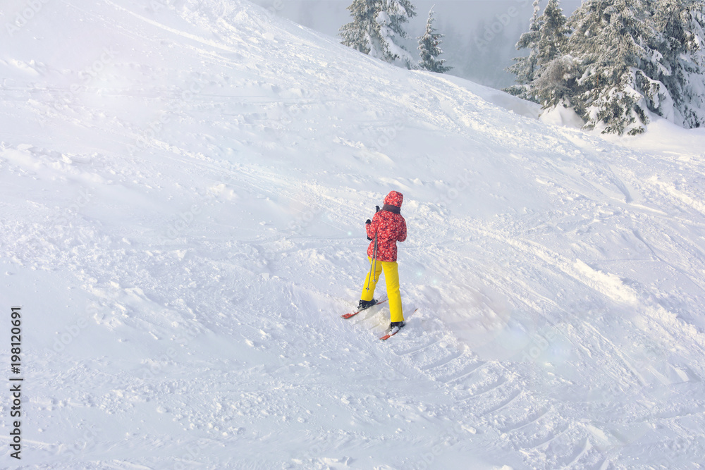 Woman on ski piste at snowy resort. Winter vacation