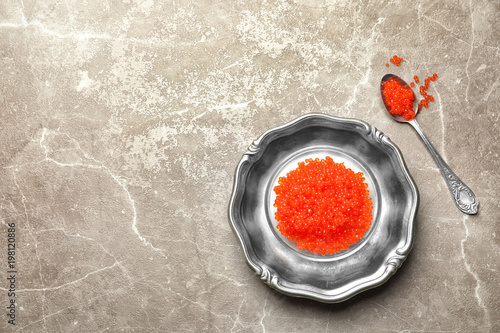 Dish with delicious red caviar on color background