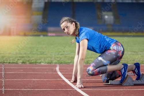 Female athlete running on the racing track on a sunny day
