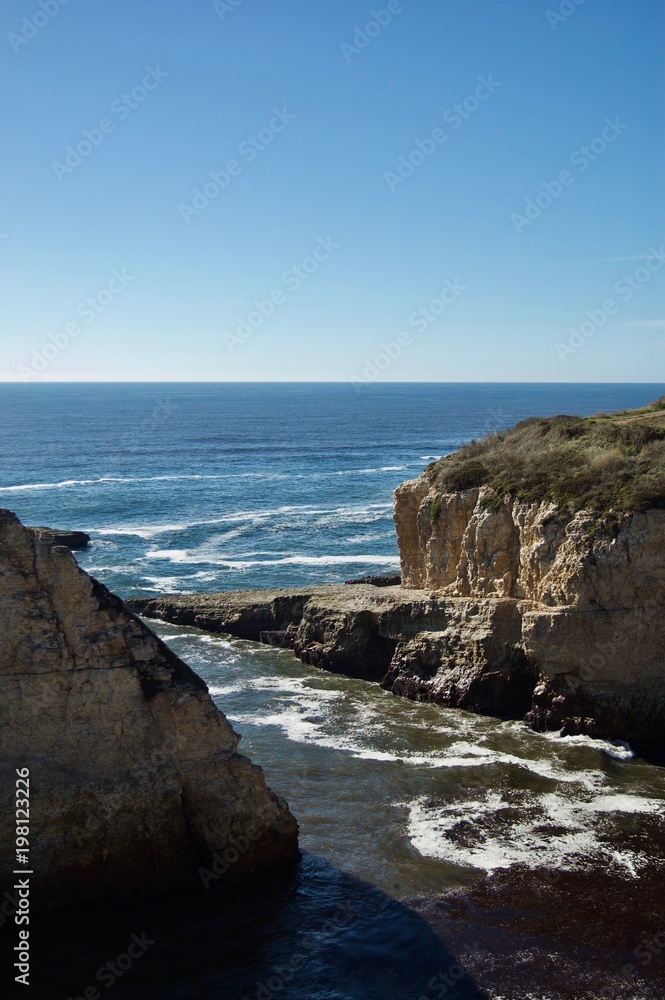 Beautiful coastal view in California (USA): Pacific ocean with limestone rock cliffs with crashing waves, a clear blue summer sky without clouds is the perfect place for tourists to visit