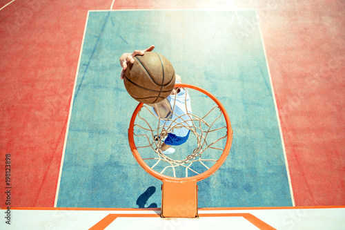 Fotobehang Young man jumping and making a fantastic slam dunk playing streetball, basketball