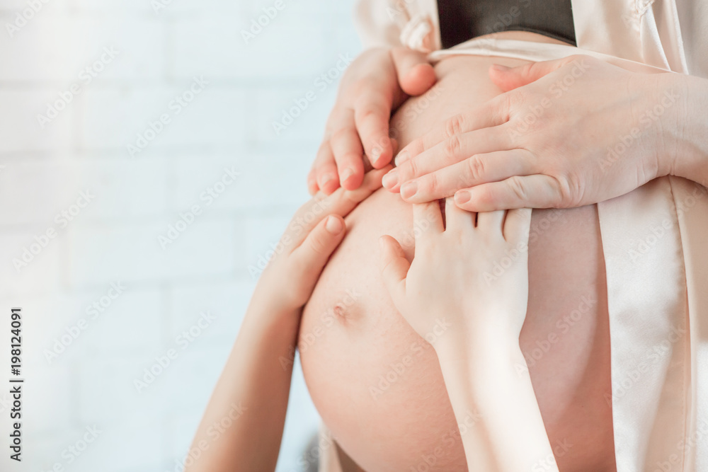 Fototapeta premium Pregnant mother and son are holding and touching tummy together