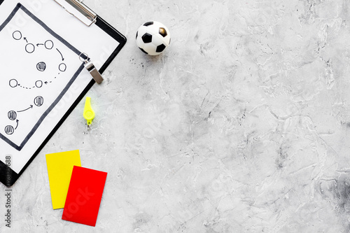 Sport judging concept. Soccer referee. Tactic plan for game, football ball, red and yellow cards, whistle on stone background top view copy space