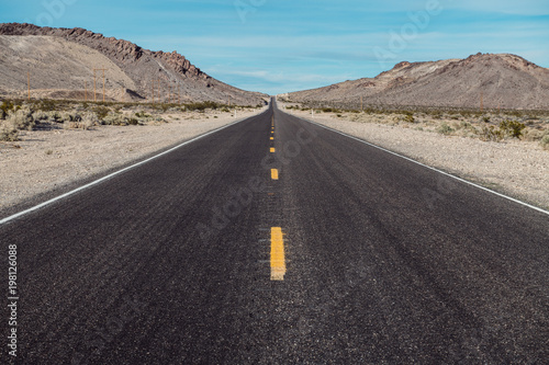 Empty scenic long straight desert road with yellow marking lines