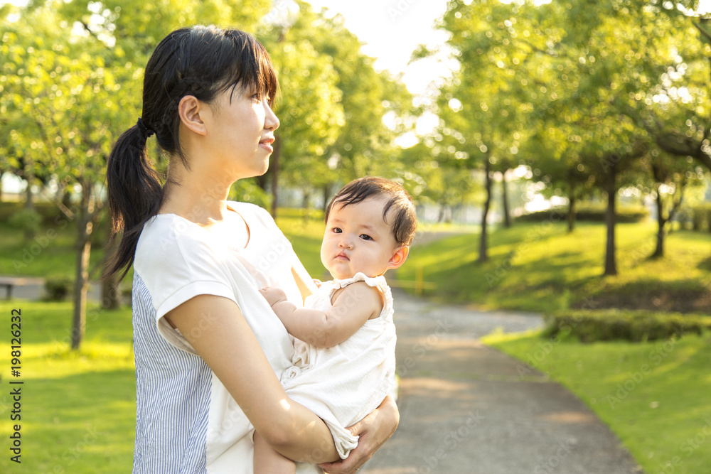 新緑の公園で赤ちゃんを抱く若い母のアップ 新緑の公園で赤ちゃんを抱く若い母のアップ