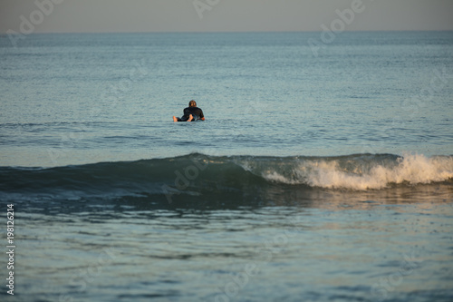 unknown surfer waits for his next wave at sunset