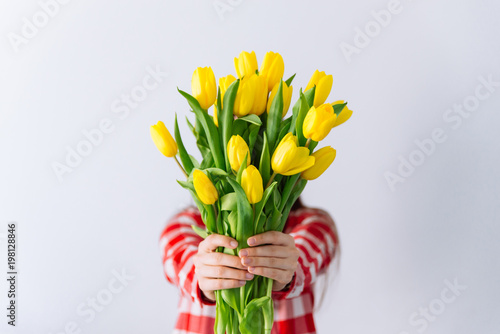 Fototapeta Naklejka Na Ścianę i Meble -  woman hold bouquet of yellow tulips. cover face with flowers. spring romantic concept