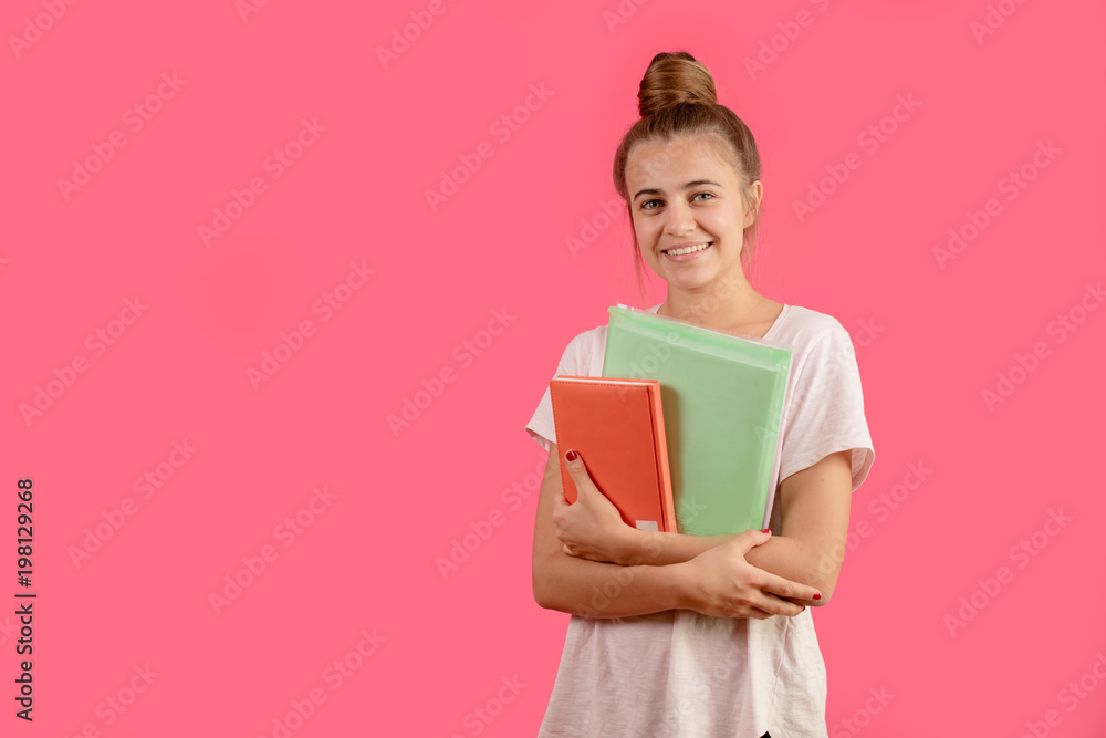 smiling young female posing with book and folder isolated on the pink background. get knowledge.study smiling young female posing with book and folder isolated on the pink background. get knowledge.study