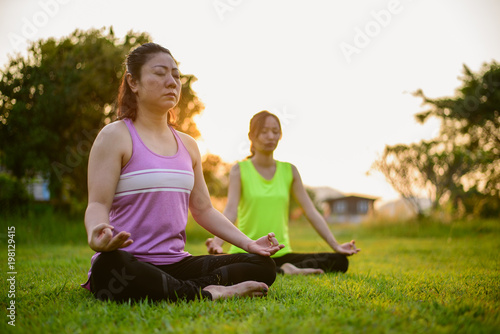 Two womans doing yoga in morning park