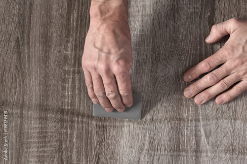 Closeup of male carpenter sticking self-adhesive wooden film