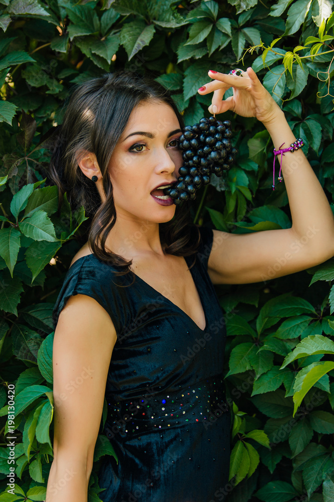 Portrait of young sexy brunette with black grapes. Portrait of young sexy brunette with black grapes.