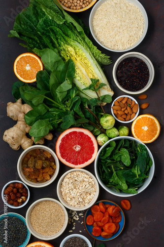 Flat lay set clean eating. Vegetarian healthy food - different vegetables and fruits, superfood, seeds, cereal, leaf vegetable on dark background top view