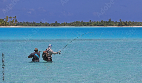 Guide pointing out a fish to fly-fisherman in turquoise waters french polynesia photo