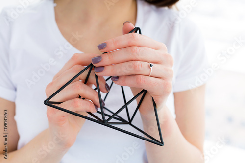 Beautiful young woman holding a metal geometric decor