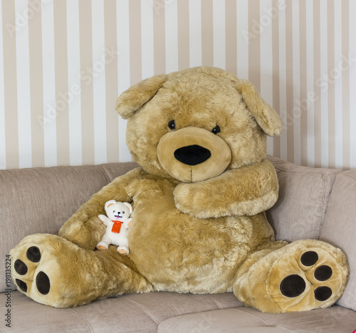 Big plush bear sitting with a little teddy bear on her side.