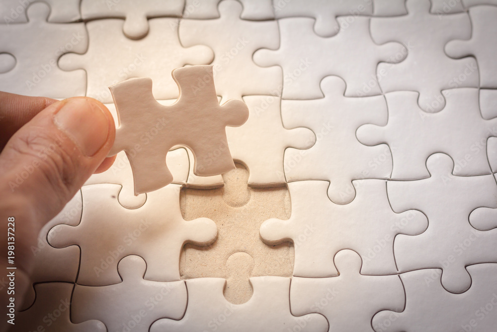 hand placing the last jigsaw puzzle piece,conceptual of problem solving hand placing the last jigsaw puzzle piece,conceptual of problem solving