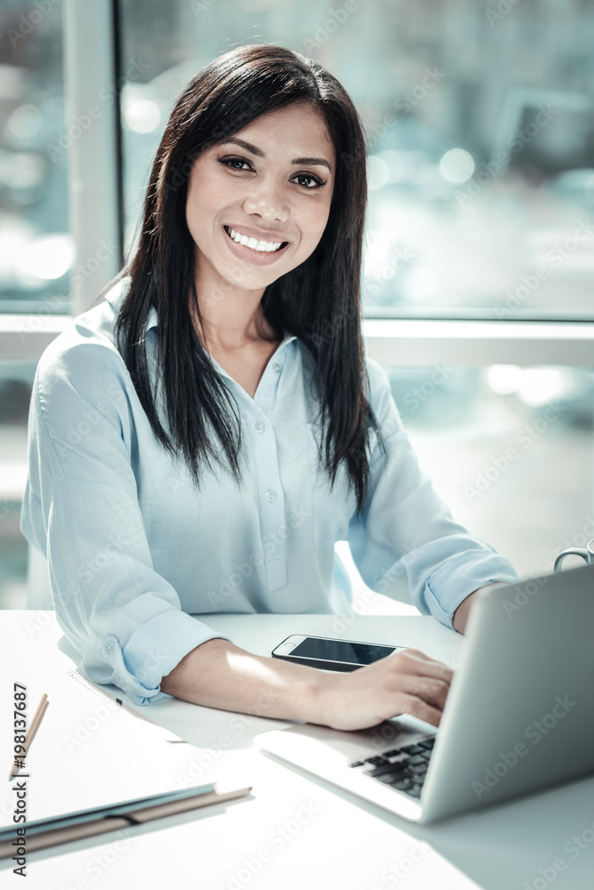 Simply work day. Pleasant pretty busy woman being on her workplace smiling and using the laptop. Simply work day. Pleasant pretty busy woman being on her workplace smiling and using the laptop.