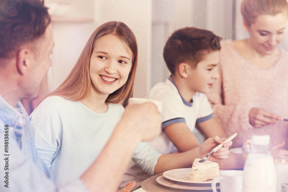 Fototapeta premium Time for dessert. Positive little female holding fork in right hand and looking at her daddy while going to eat cake
