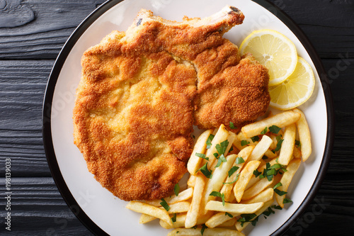 Veal alla Milanese (cotoletta alla milanese) with French fries close-up on a plate. horizontal top view