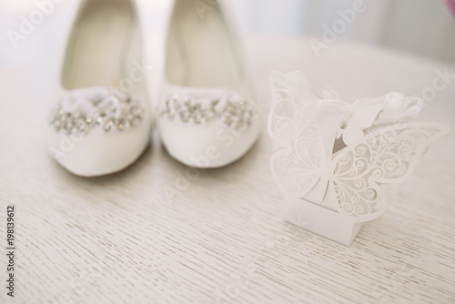 Elegant women's wedding shoes with rhinestones on a light background, the fees of the bride, selective focus