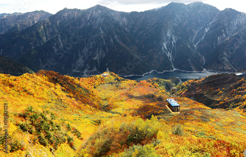 Aerial panorama of a scenic cable car flying over the beautiful autumn valley in Tateyama Kurobe Alpine Route, Toyama Japan ~ A magnificent view from Daikanbo over Kurobe dam & colorful autumn valley