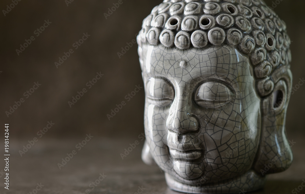 Buddha head statue standing on a dark stone surface Buddha head statue standing on a dark stone surface