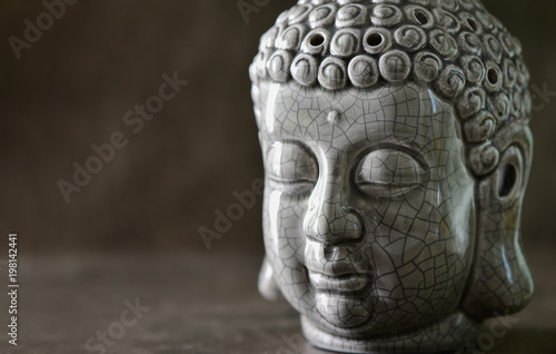 Buddha head statue standing on a dark stone surface