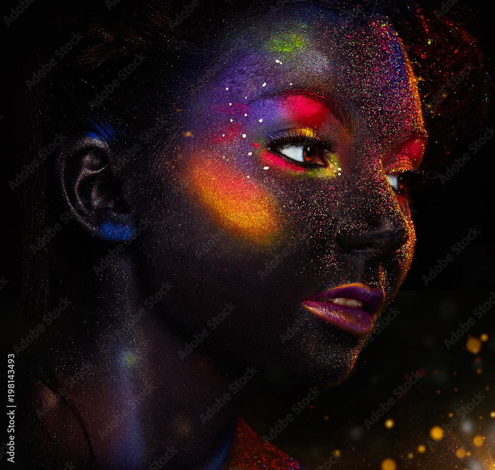 Glowing neon makeup with dramatic look in his eyes. Creative body art on  the theme of space and stars. Amazing close-up portrait glow in the dark  makeup. Stock Photo