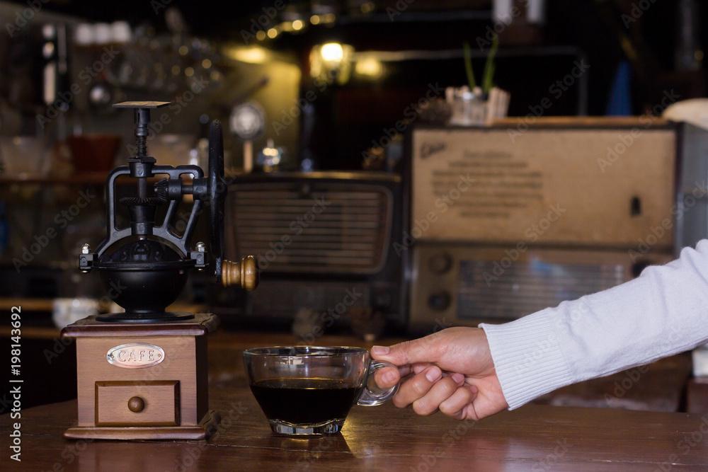 A woman holding a cup of coffee on a wooden background. A woman holding a cup of coffee on a wooden background.