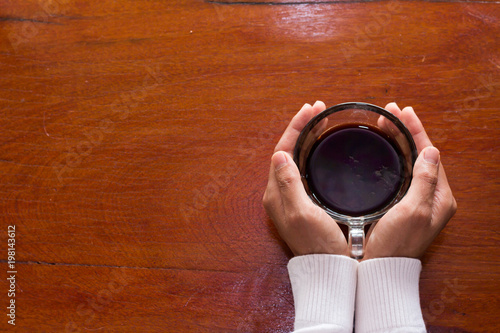 A woman holding a cup of coffee on a wooden background.