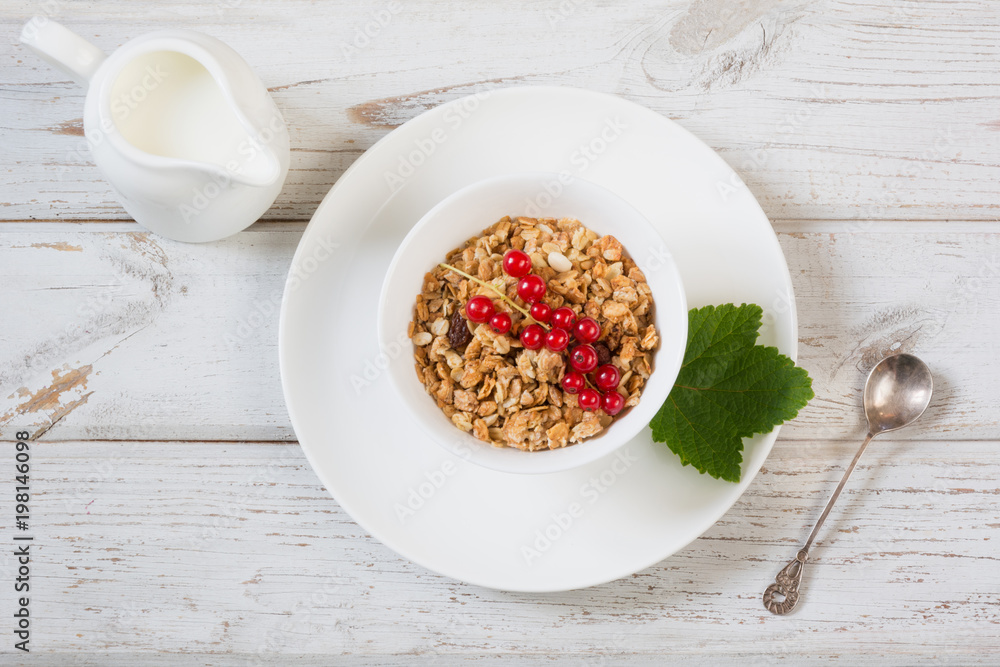 Summer healthy breakfast of granola, muesli with milk jug with red currant decor on light wooden board. Top view. Summer healthy breakfast of granola, muesli with milk jug with red currant decor on light wooden board. Top view.
