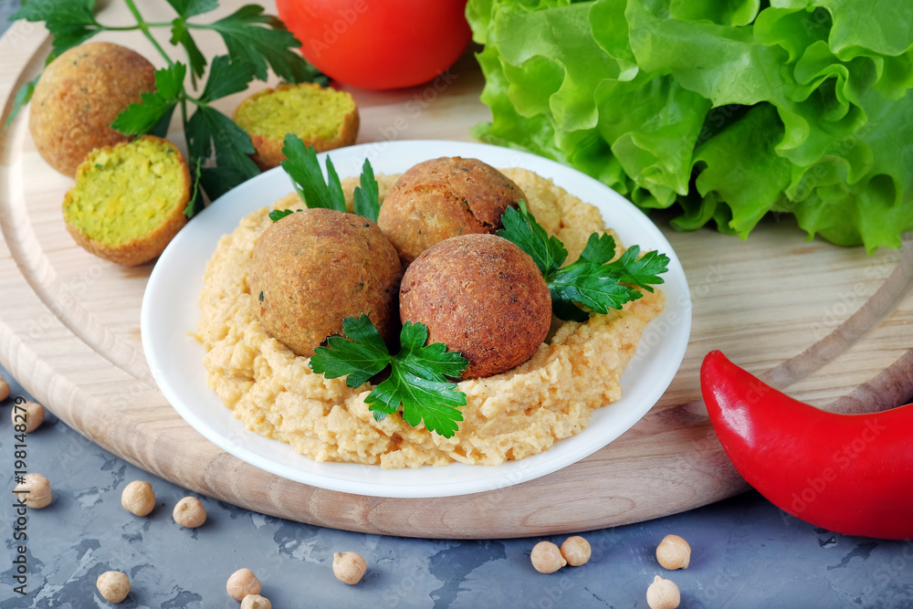 Falafel balls and bowl with hummus on cutting board. Vegetarian and vegan healthy food. Falafel balls and bowl with hummus on cutting board. Vegetarian and vegan healthy food.
