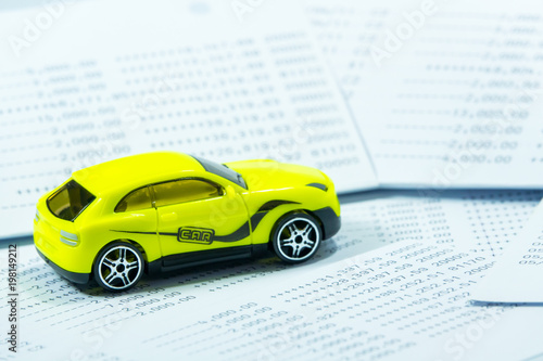 Car toy on saving statement bank book background.