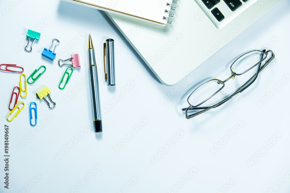 Top view of laptop, blank notebook, paper clips and smart phone with white background and copy space. Top view of laptop, blank notebook, paper clips and smart phone with white background and copy space.