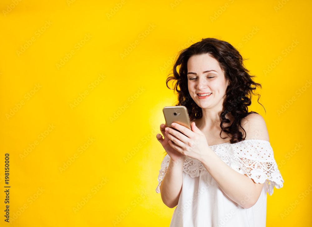 Woman holding smartphone over yellow background Woman holding smartphone over yellow background