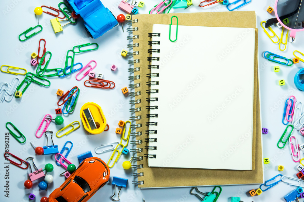 Top view of laptop, blank notebook, paper clips and smart phone with white background and copy space. Top view of laptop, blank notebook, paper clips and smart phone with white background and copy space.