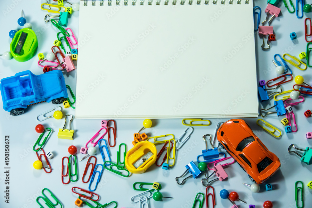 Top view of laptop, blank notebook, paper clips and smart phone with white background and copy space. Top view of laptop, blank notebook, paper clips and smart phone with white background and copy space.