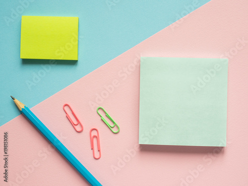 Business flat lay with copy space on a background divided in half pink and blue Notebooks to write text stickers Pencil, Stationery color paper clip. photo