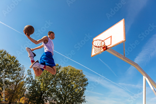 Young Basketball street player making slam dunk