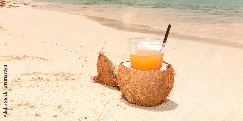 fresh coconut orange cocktail juice on tropical sand beach