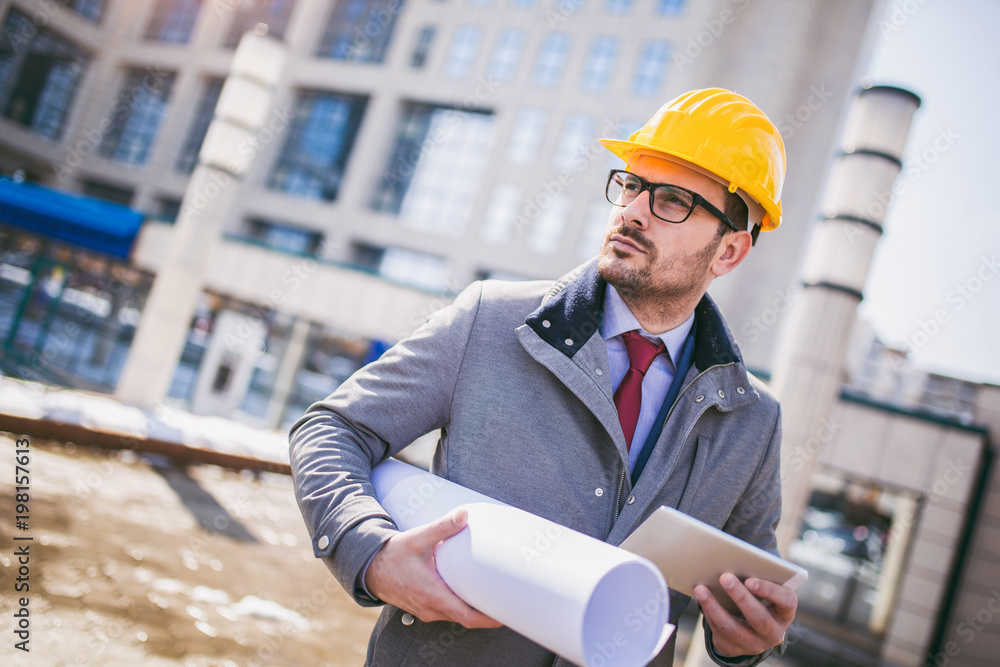 Architect in protective helmet using digital tablet in front of office building Architect in protective helmet using digital tablet in front of office building