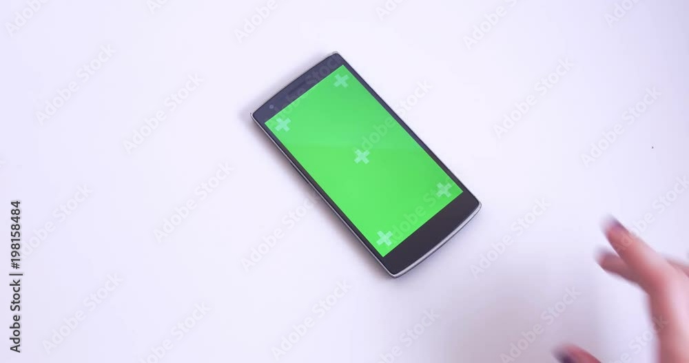 Hand Taking Smart Phone With Green Chroma Screen From White Table Closeup Hand Taking Smart Phone With Green Chroma Screen From White Table Closeup