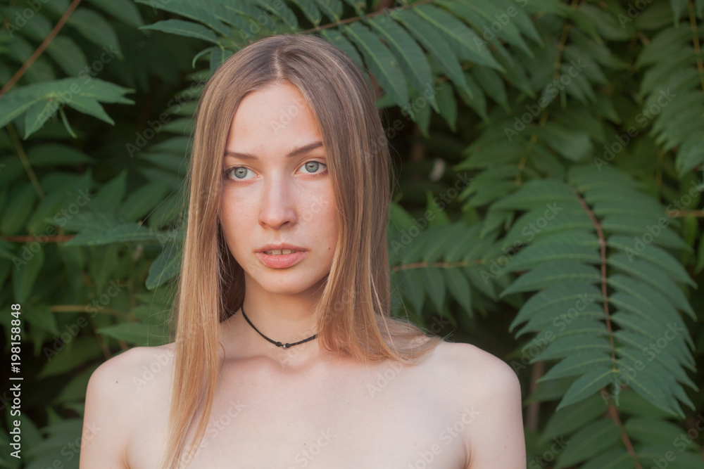 Portrait of beautiful young woman in green leaves, blonde pretty lady in spring bushes Portrait of beautiful young woman in green leaves, blonde pretty lady in spring bushes
